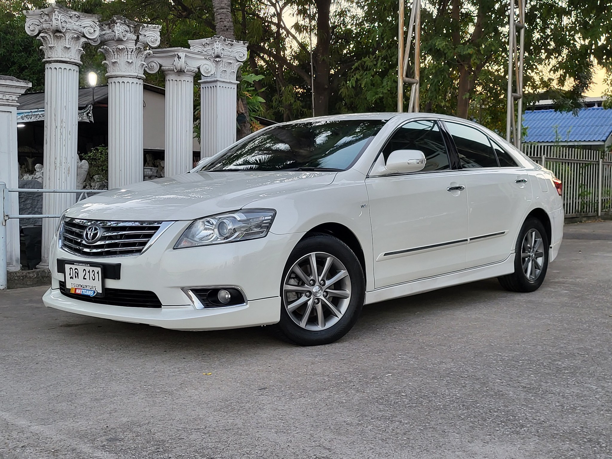 A white car parked in front of a backdrop with white Roman columns, representing a luxurious and comfortable limousine service.