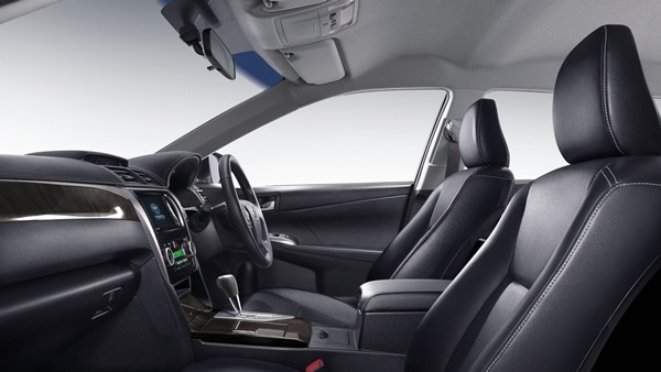 An interior view of a Toyota Camry Extremo, showcasing a predominantly black cabin with black leather seats accented by red stitching, and carbon fiber-patterned interior trim elements. A large touchscreen display with the Toyota logo is centrally located on the console. The instrument cluster features blue-illuminated gauges, and the steering wheel is a multi-function type. The overall interior design appears sporty and luxurious.
