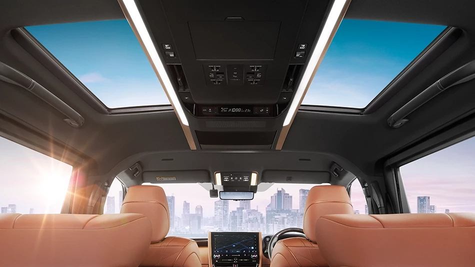 Interior of a luxurious limousine with light brown leather seats, a display screen on the central console, and a panoramic glass roof offering views of the sky and cityscape.